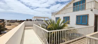 a balcony of a white building with blue shutters at Chic Surf-Inspired Mezzanine Studio 