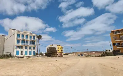 a dirt road with a building and a palm tree at Chic Surf-Inspired Mezzanine Studio 