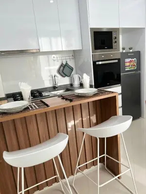 a kitchen with two white bar stools and a counter at Apartamento Batuku in Praia