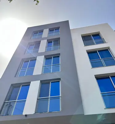 a white building with blue windows at Apartamento Ilhas in Praia
