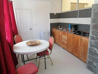 a kitchen with a white table and red chairs at STUDIO VUE MER - CASA da LUZ in Mindelo