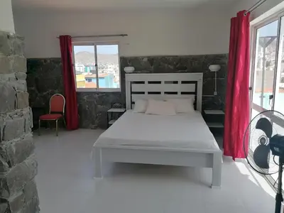 a bedroom with a bed and a red curtain at STUDIO VUE MER - CASA da LUZ in Mindelo