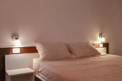 a bed in a bedroom with two lights on the wall at Duarte Apartments - Las Rochas in Mindelo