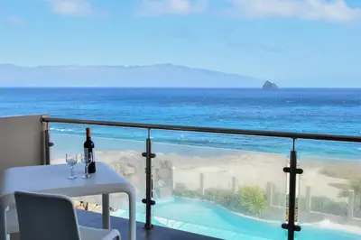 a table with a bottle of wine on a balcony overlooking the ocean at Duarte Apartments - Las Rochas in Mindelo