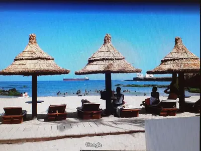 a group of people sitting on the beach under umbrellas at Gamboa-1 Praia in Praia