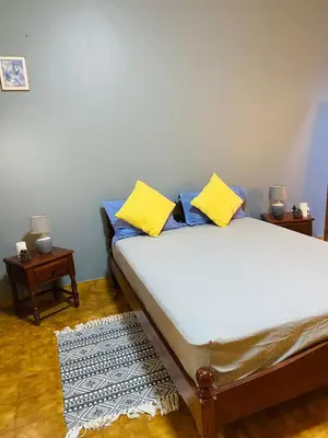 a bedroom with a bed with yellow pillows and a rug at Huizenmarkt Caboverde in Mindelo