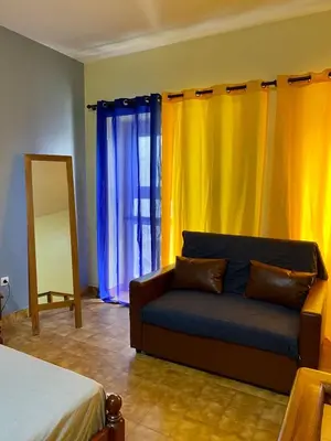 a living room with a couch and yellow curtains at Huizenmarkt Caboverde in Mindelo
