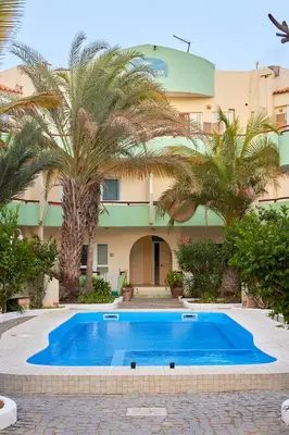 a pool in front of a building with palm trees at Casa Irma in Santa Maria