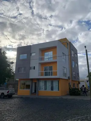 a building on a street with a cloudy sky at Vannimar t2 in Porto Novo