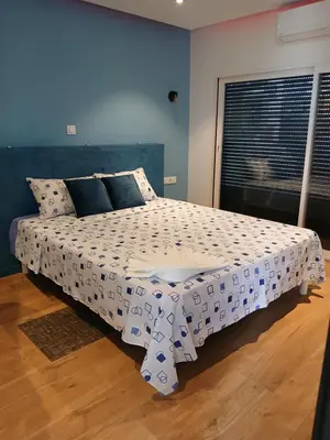 a bedroom with a bed with a white comforter at Casa Cantinho d`ouro in Ponta do Sol