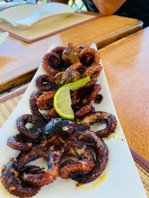 a plate of octopus with a lime on a table at Fajã Beach House in Fajã