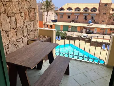 a balcony with a wooden table and a swimming pool at Time Out DjadSal Residence AC Wifi in Santa Maria