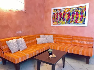 an orange couch sitting under a painting on a wall at Time Out DjadSal Residence AC Wifi in Santa Maria