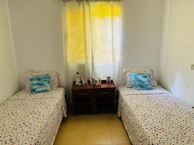 a bedroom with two beds and a table and a window at City Center Near Beach B&B in Tarrafal