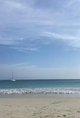 a beach with a sail boat in the ocean at Coral beach house in Santa Maria