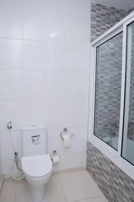 a white toilet in a bathroom with a window at Nice And Modern with king size bed in Praia
