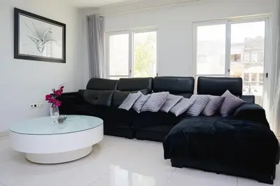 a living room with a black couch and a table at Nice And Modern with king size bed in Praia