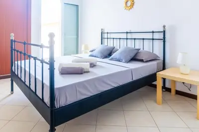 a large bed with blue pillows in a bedroom at Bliss Apartments - T2 Nicole in Mindelo