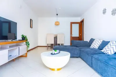 a living room with a blue couch and a tv at Bliss Apartments - T2 Nicole in Mindelo