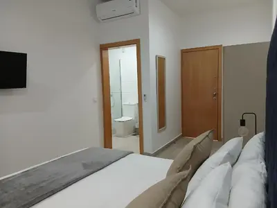 a bedroom with a white bed and a bathroom at Charming House Tarrafal in Tarrafal