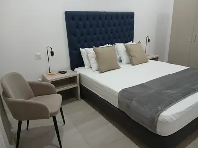 a bedroom with a large bed and a chair at Charming House Tarrafal in Tarrafal