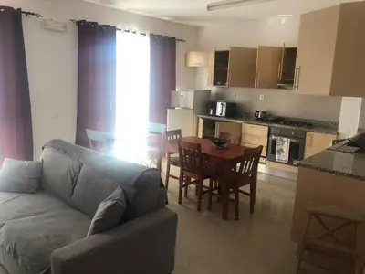 a living room with a couch and a table and a kitchen at Apartamento Oiá Mindelo in Mindelo