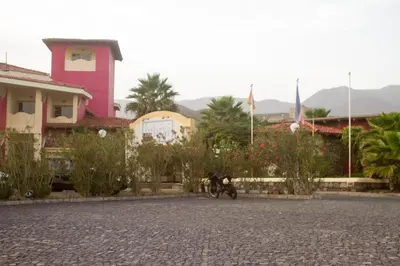 a motorcycle parked in front of a pink building at Hotel Santantao Art Resort in Porto Novo
