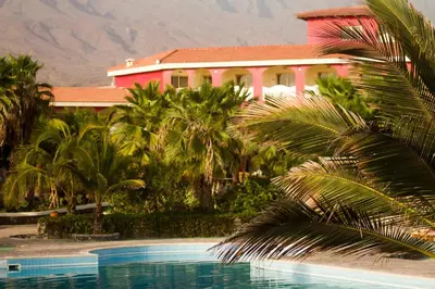 a house with a palm tree in front of a pool at Hotel Santantao Art Resort in Porto Novo