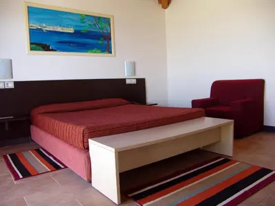 a bedroom with a bed and a red chair at Hotel Santantao Art Resort in Porto Novo
