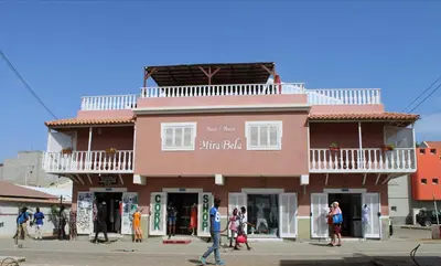 a pink building with people walking in front of it at Hotel MiraBela in Santa Maria