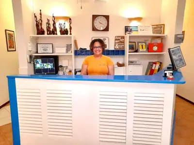 a woman standing behind a blue and white counter at Hotel MiraBela in Santa Maria