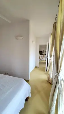 a bedroom with a white bed and a hallway at Surf House Casa Vehla in Sal Rei