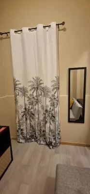 a shower curtain with palm trees on it next to a mirror at City Center Mindelo 37 in Mindelo