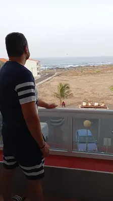 a man looking out of a window at the beach at Edu Horizonte in Calheta de São Miguel