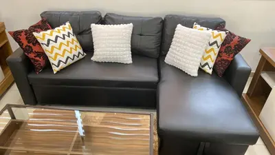a black leather couch with pillows on it at Apartamento em Pedra Badejo in Pedra Badejo