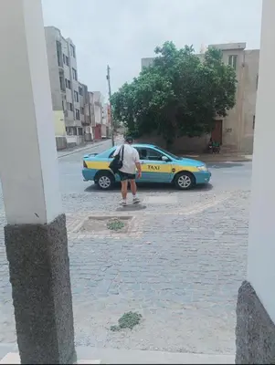a man riding a skateboard in front of a taxi at 1 chambre proche aeroporto cabo verde in Espargos