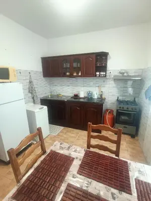 a kitchen with wooden cabinets and a white refrigerator at 1 chambre proche aeroporto cabo verde in Espargos