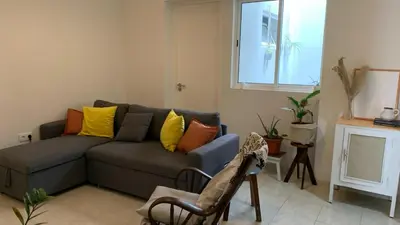 a living room with a gray couch with yellow and orange pillows at Flat Mindelo 30 in Mindelo