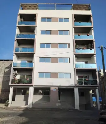 a tall white apartment building with balconies at Meraki's Apartment in Praia