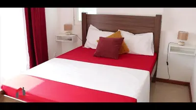 a bedroom with a large bed with white and red sheets at Guest House Lina Elisa in Mindelo