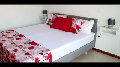 a bed with red and white sheets and pillows at Guest House Lina Elisa in Mindelo