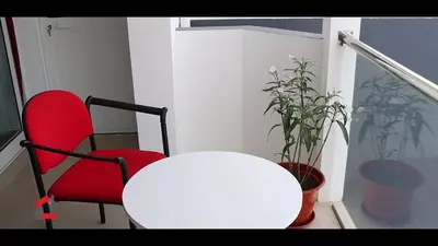 a white table and a red chair and a table and a plant at Guest House Lina Elisa in Mindelo