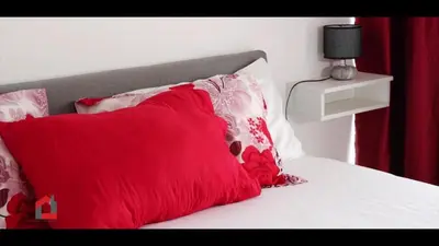 a red pillow sitting on a bed with red and white pillows at Guest House Lina Elisa in Mindelo