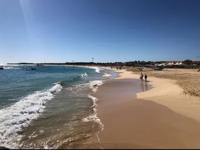 a group of people walking on the beach at Oceanfront Apt 25 Porto Antigo II in Santa Maria