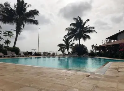 a large swimming pool with palm trees and chairs at Oceanfront Apt 25 Porto Antigo II in Santa Maria