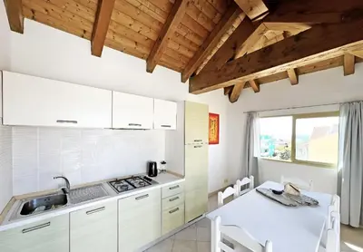 a kitchen with white cabinets and a white table and chairs at Bright Top Floor with Terrace in Santa Maria