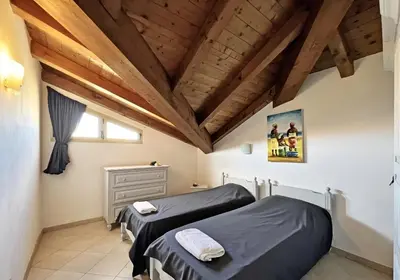 two beds in a room with wooden ceilings at Bright Top Floor with Terrace in Santa Maria