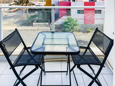 a glass table and two chairs on a balcony at Apartamento Paradise in Santa Maria