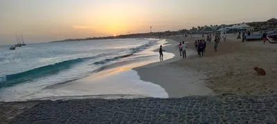 a group of people walking on the beach at sunset at Appartamento t0 n 7 situato complesso turistico porto antico 2 in Santa Maria