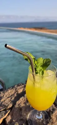 a drink with a straw in a glass next to the water at Cabo Verde Beach Sport Resort in Porto Novo